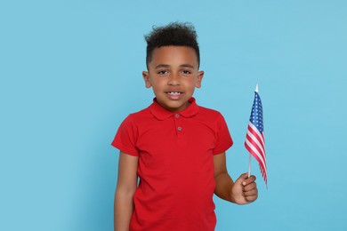 4th of July - Independence Day of USA. Boy with American flag on light blue background