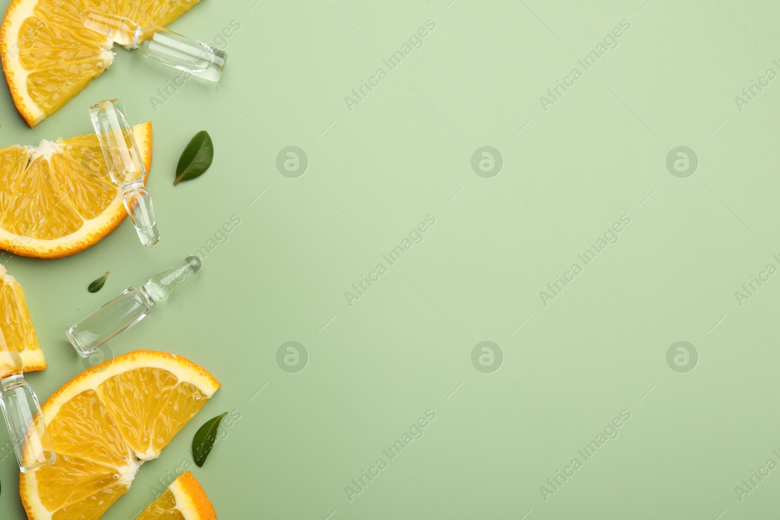 Photo of Skincare ampoules with vitamin C, slices of orange and leaves on light green background, flat lay. Space for text