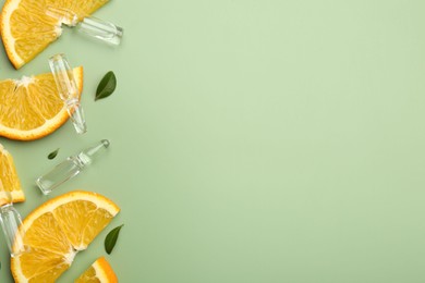 Photo of Skincare ampoules with vitamin C, slices of orange and leaves on light green background, flat lay. Space for text