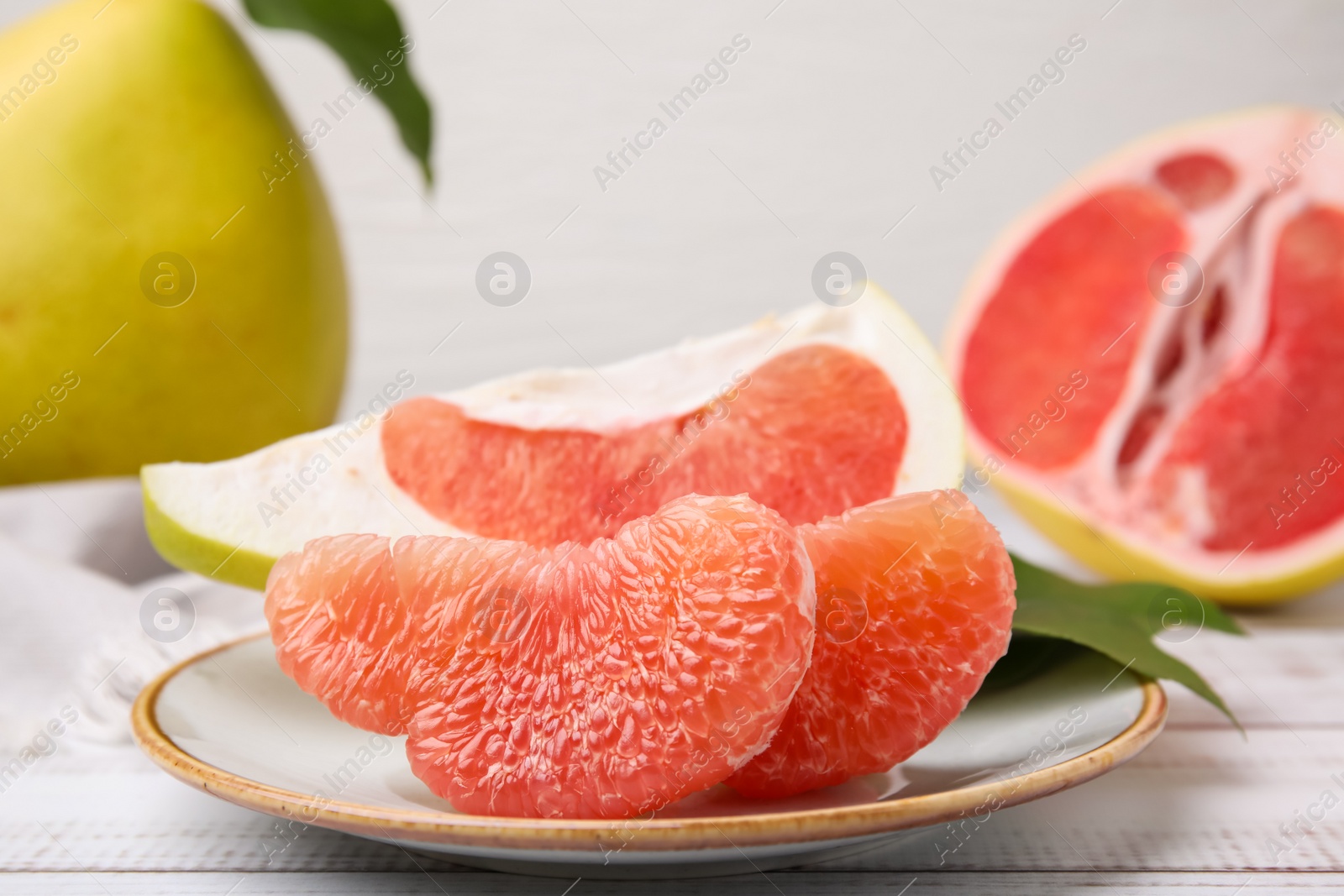 Photo of Tasty pomelo fruits on white wooden table, closeup