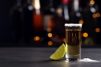 Photo of Mexican Tequila shot with lime and salt on bar counter. Space for text