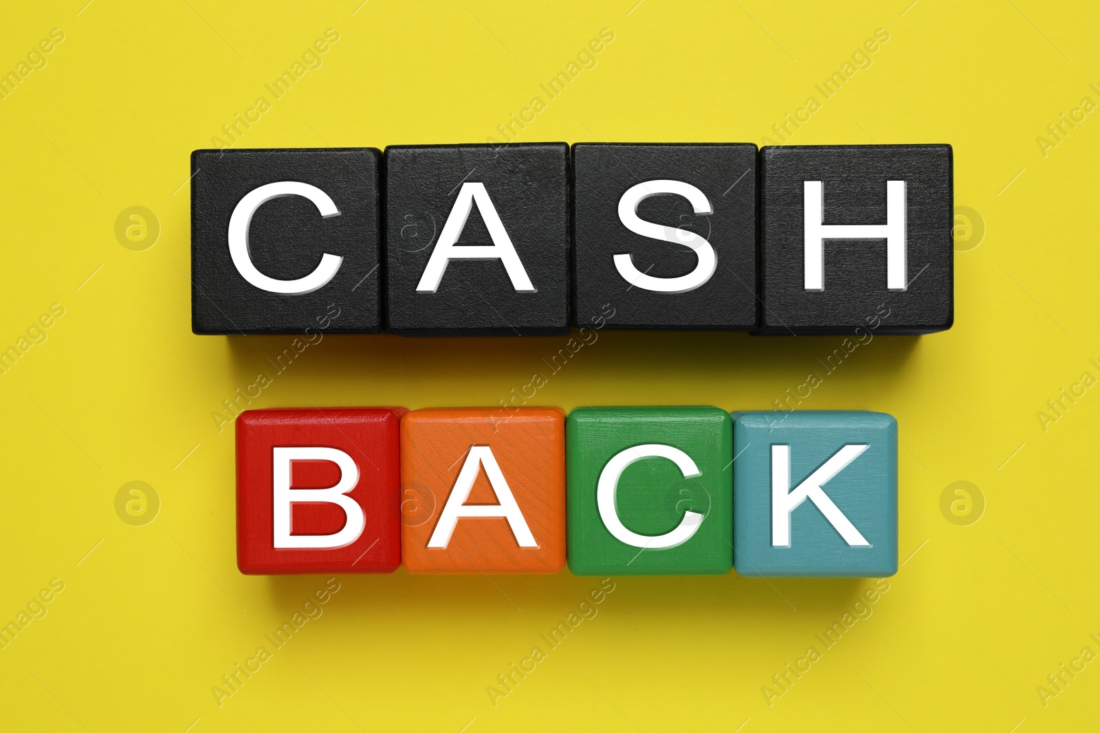 Photo of Word Cashback made with cubes on yellow background, flat lay