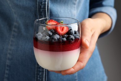 Photo of Woman holding glass dish delicious panna cotta with berries, closeup