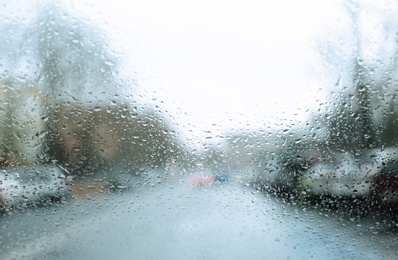 Photo of Blurred view of road through wet car window. Rainy weather