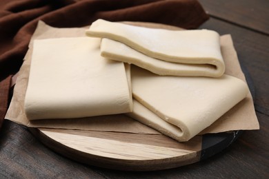 Raw puff pastry dough on wooden table, closeup