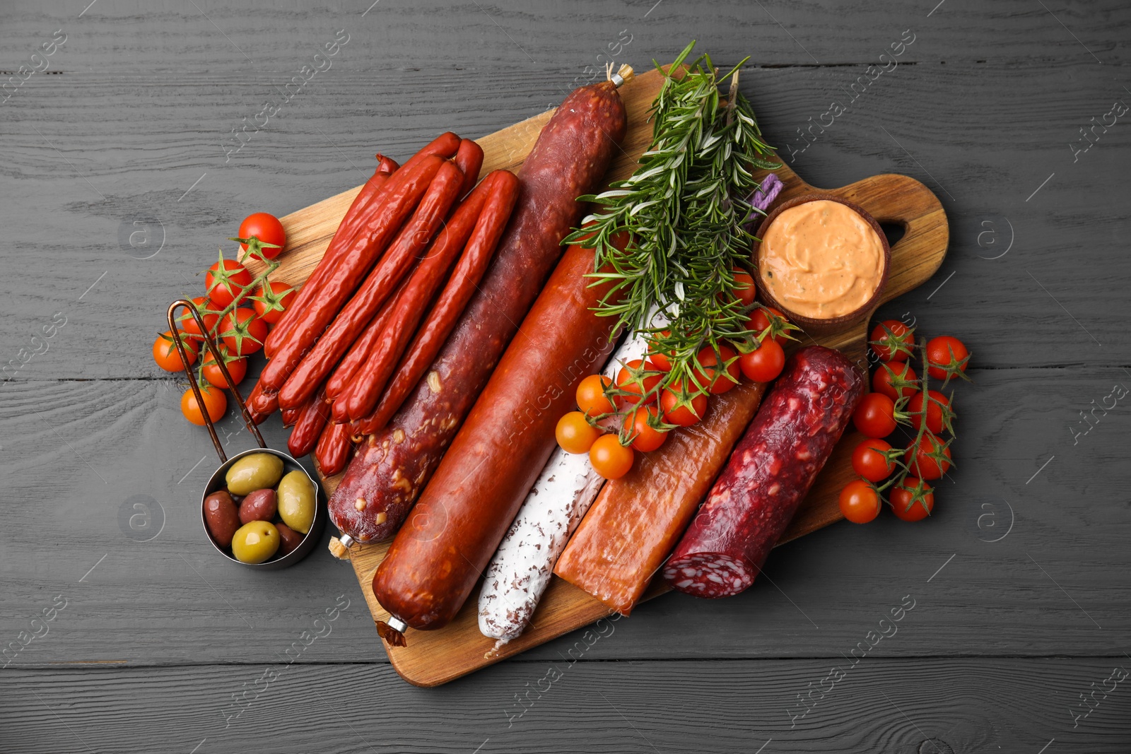 Photo of Different types of tasty sausages on grey wooden table, flat lay