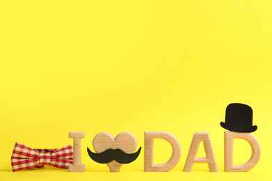 Photo of Phrase I LOVE DAD on yellow background. Happy Father's Day