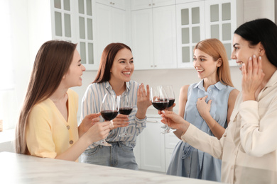 Photo of Beautiful young ladies with wine in kitchen. Women's Day