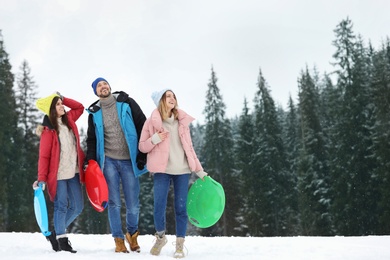 People with plastic sleds outdoors. Winter vacation