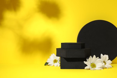 Photo of Many black geometric figures and flowers on yellow background, space for text. Stylish presentation for product