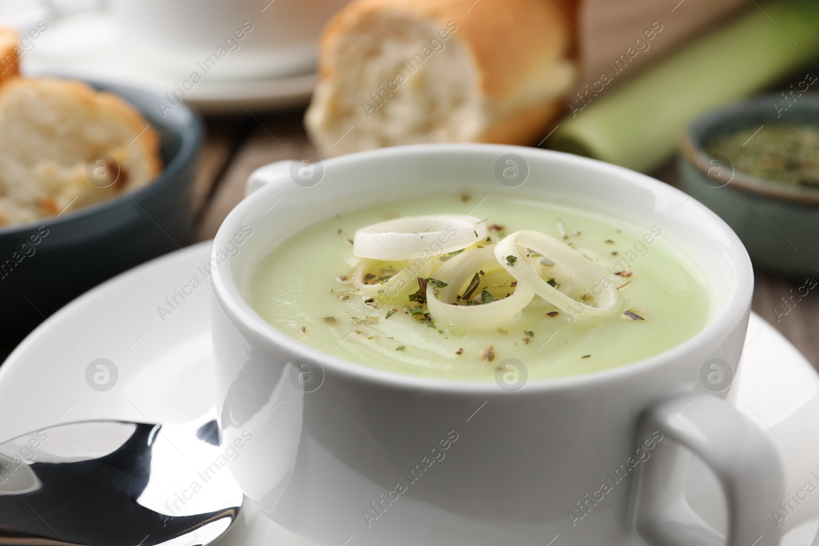 Photo of Delicious cream soup with leek and spices in bowl on table, closeup