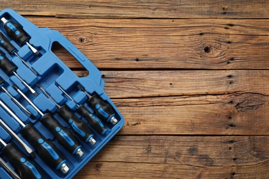 Set of screwdrivers in open toolbox on wooden table, top view. Space for text