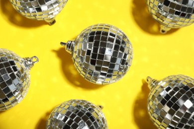 Photo of Shiny disco balls on yellow background, flat lay