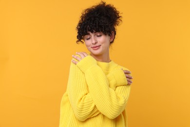 Young woman in stylish warm sweater on yellow background