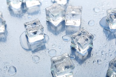 Melting ice cubes and water drops on light background, closeup