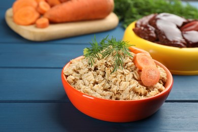 Photo of Natural pet food in feeding bowls on blue wooden table, closeup