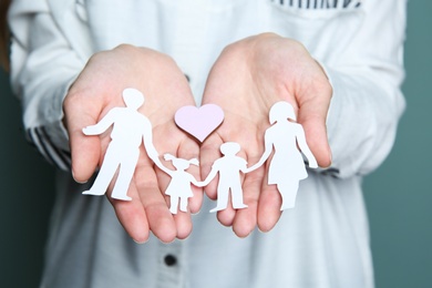 Woman holding heart and paper family cutout, closeup