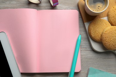 Open notebook, pen, coffee and cookies on wooden table, flat lay