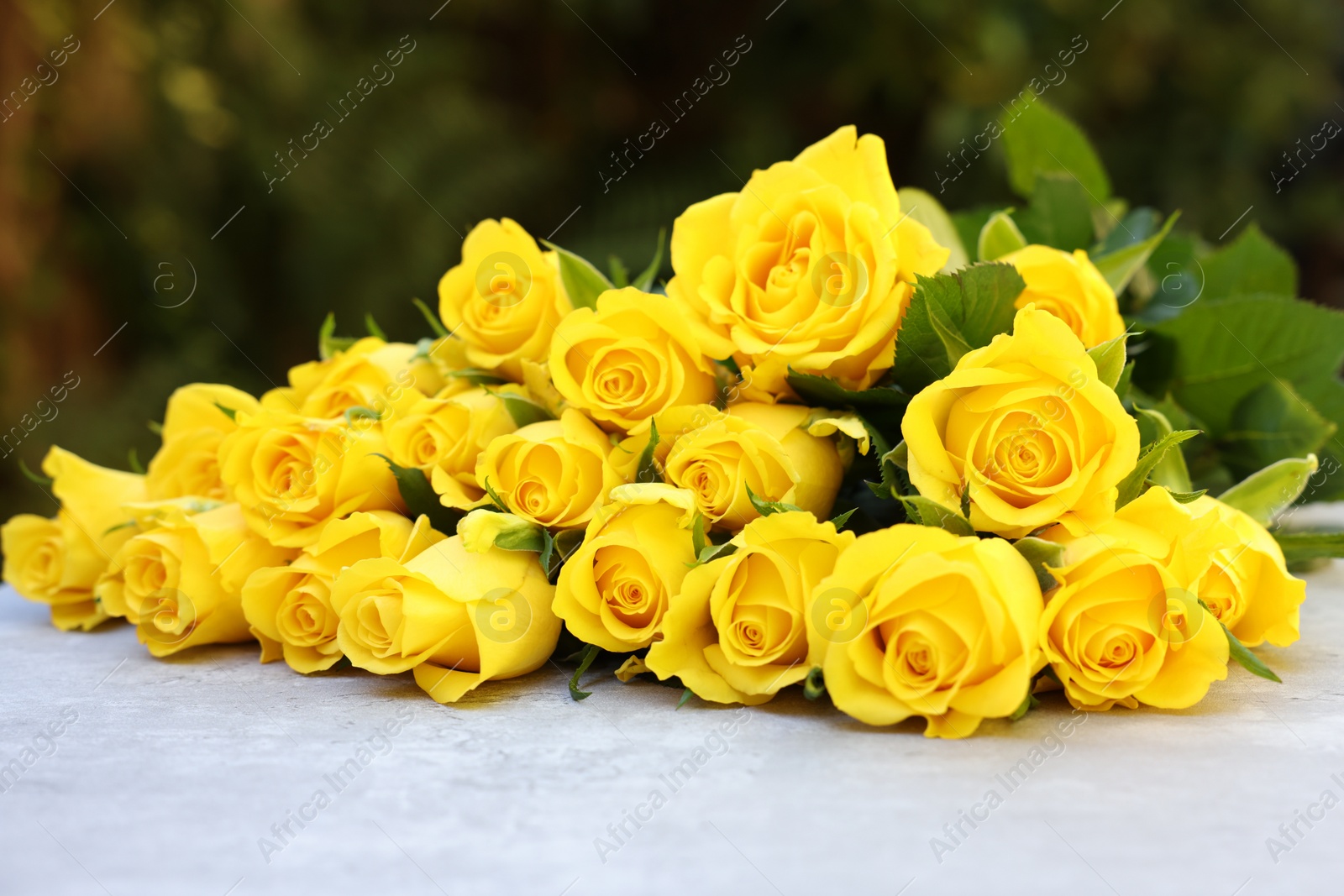 Photo of Beautiful bouquet of yellow roses on light table outdoors