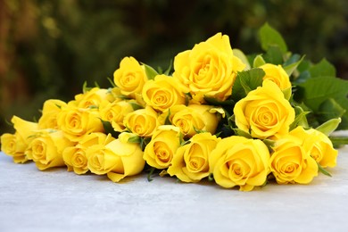 Beautiful bouquet of yellow roses on light table outdoors