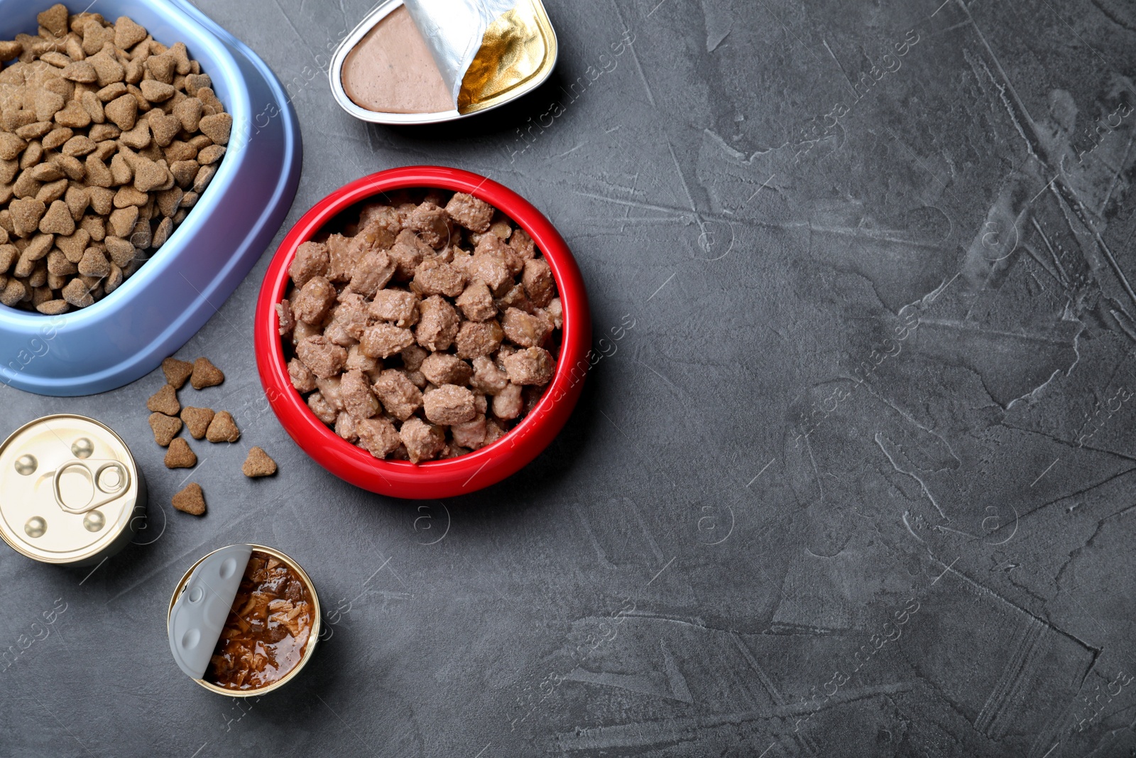 Photo of Wet and dry pet food on grey table, flat lay. Space for text