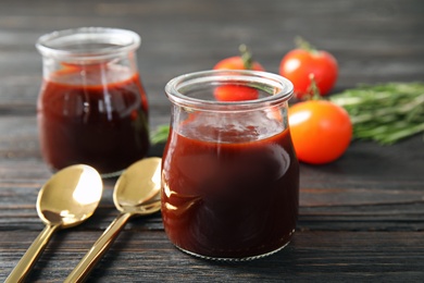 Glass jar of barbecue sauce and spoons on wooden table