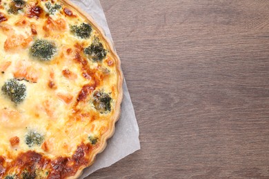 Delicious homemade quiche with salmon and broccoli on wooden table, top view. Space for text