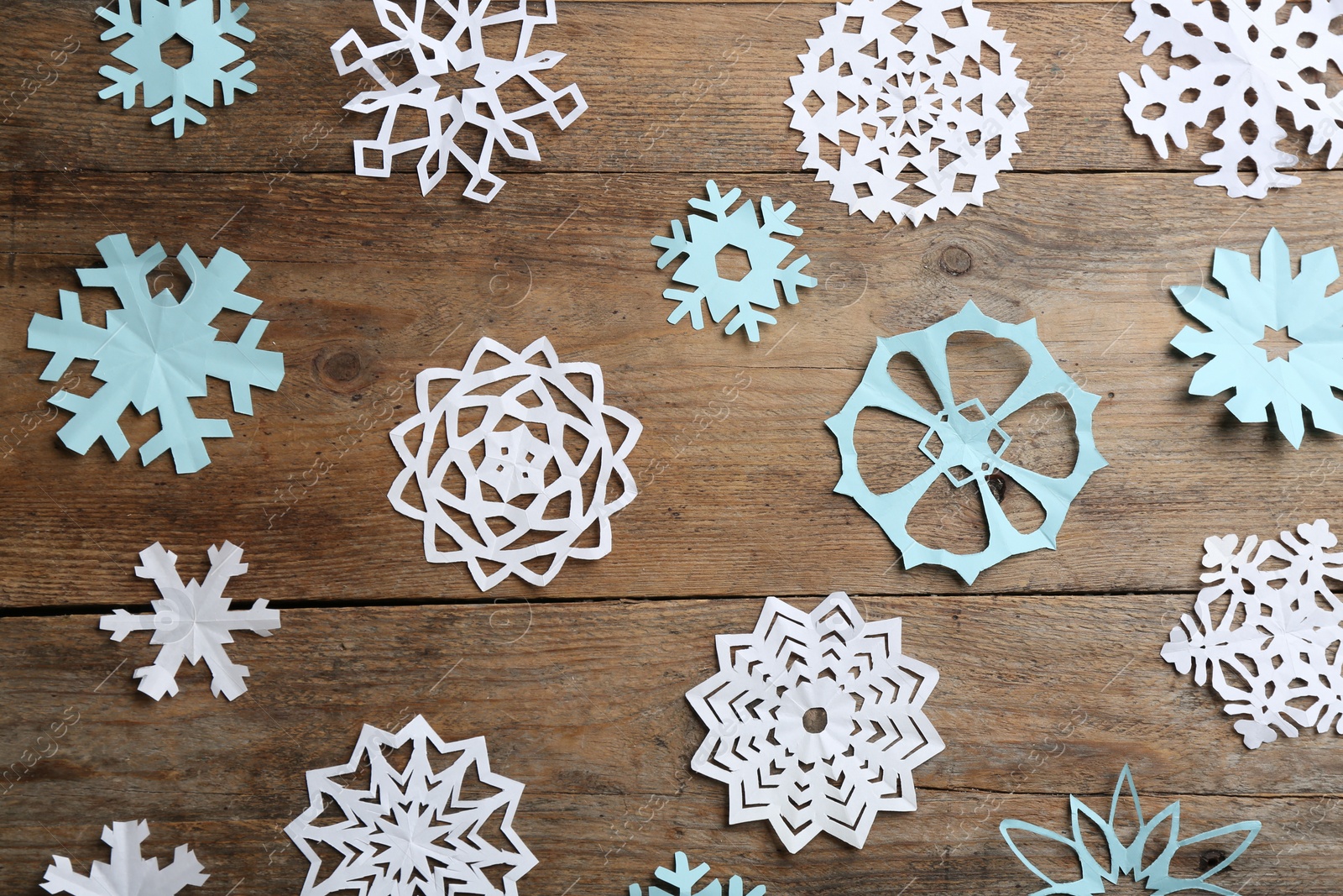 Photo of Many paper snowflakes on wooden background, flat lay
