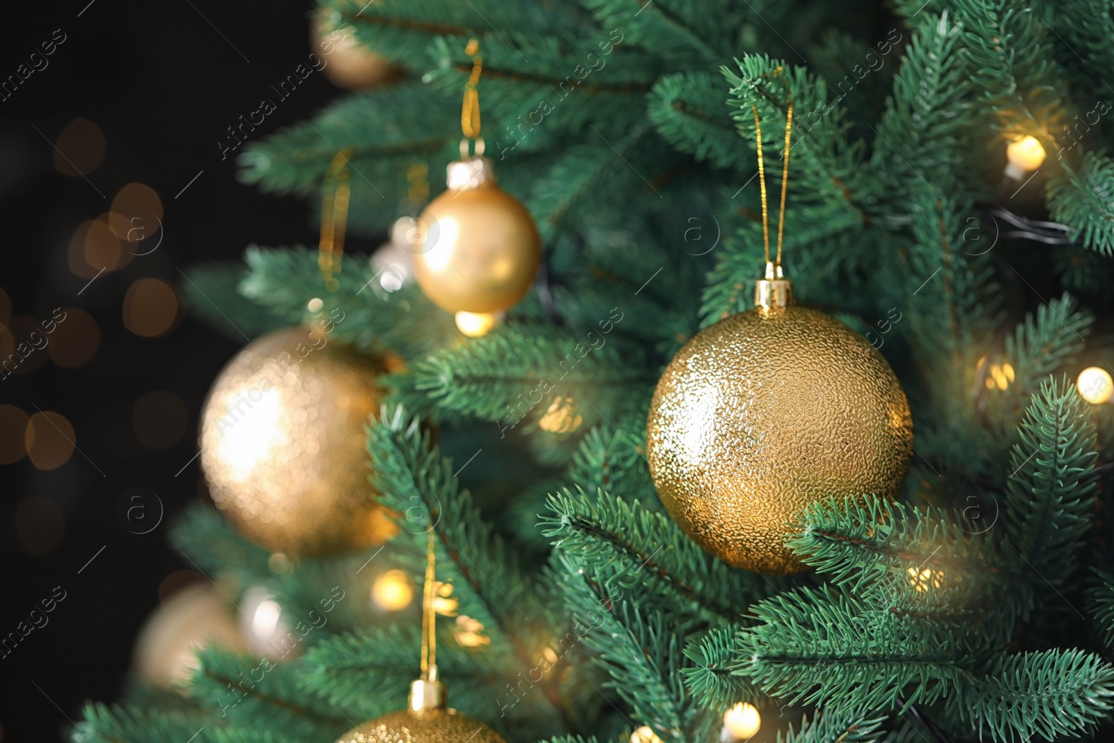 Photo of Beautiful Christmas tree with festive decor against blurred lights on background, closeup