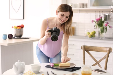 Photo of Young blogger taking photo of food in kitchen