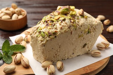 Photo of Piece of tasty halva with pistachios and mint on table, closeup