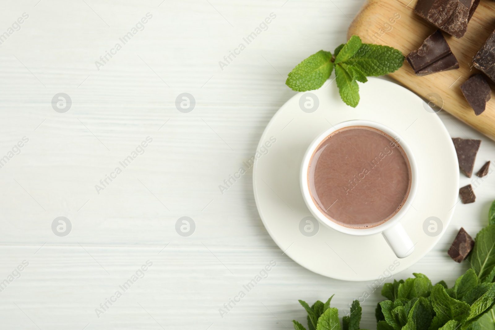 Photo of Cup of delicious hot chocolate, chunks and fresh mint on white wooden table, flat lay. Space for text