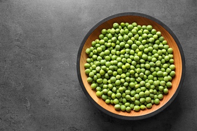 Plate with green peas on grey background, top view