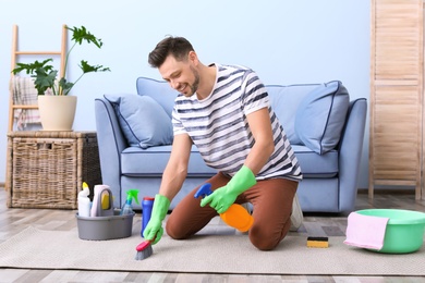 Photo of Mature man cleaning carpet at home