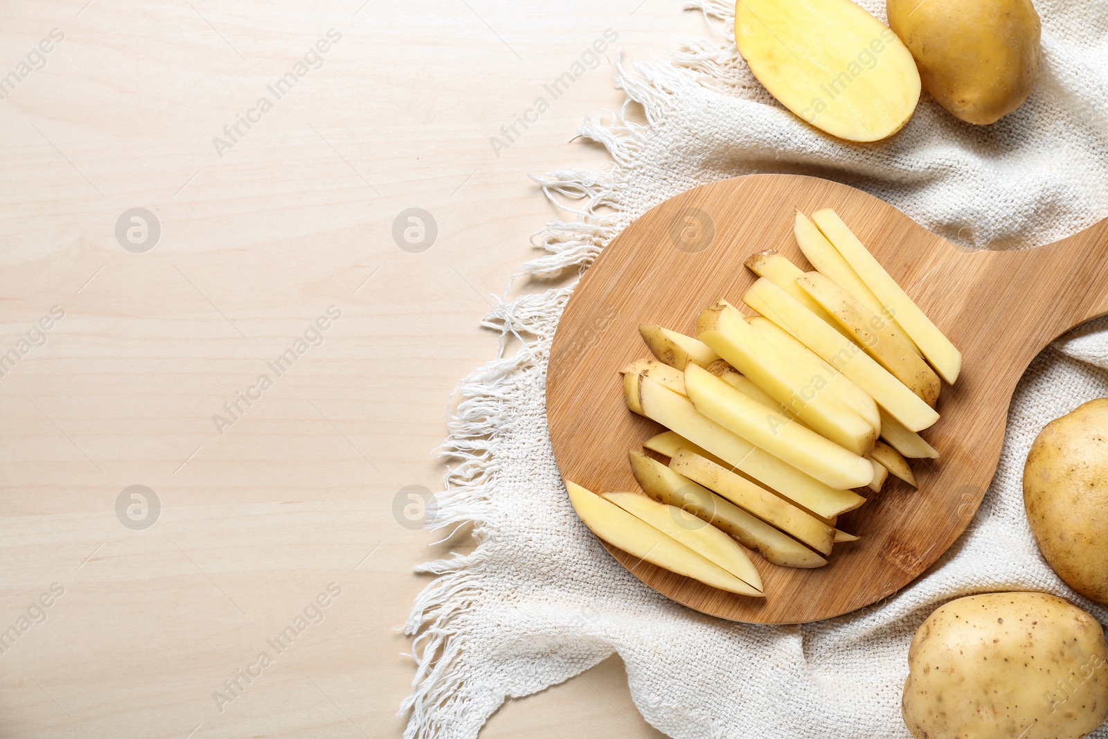 Photo of Cut and whole raw potatoes on white wooden table, flat lay. Space for text