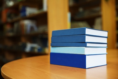 Photo of Stack of books on table in library. Space for text