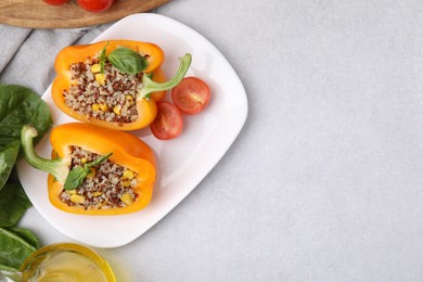 Photo of Quinoa stuffed bell pepper with basil and tomato on light table, top view. Space for text