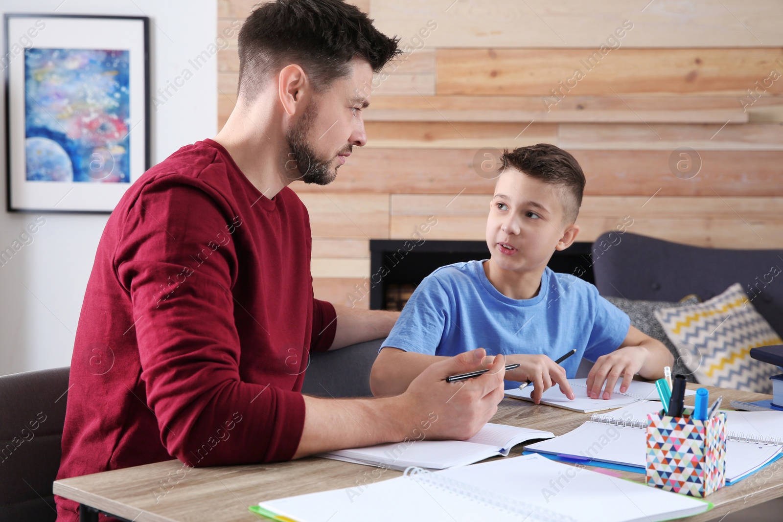 Photo of Dad helping his son with homework in room