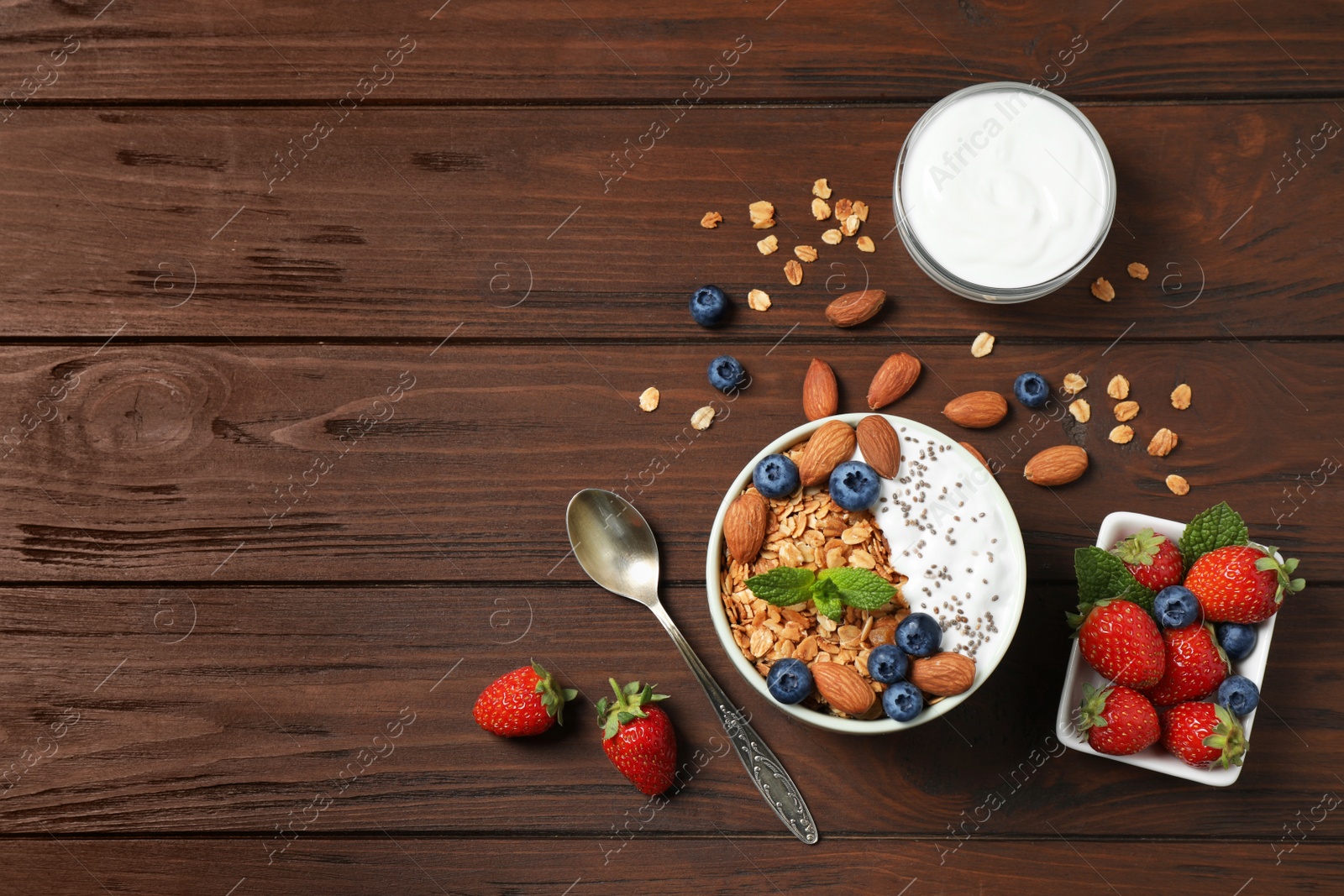 Photo of Healthy homemade granola with yogurt on wooden table, flat lay. Space for text