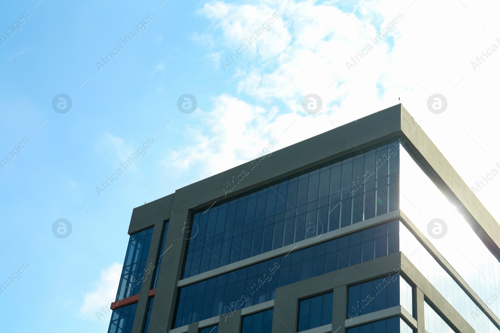 Photo of Modern skyscraper under blue sky with clouds, low angle view