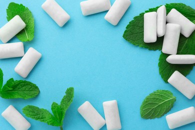 Photo of Frame made of tasty white chewing gums and mint leaves on light green background, flat lay. Space for text