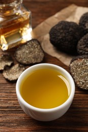 Photo of Fresh truffle oil in bowl on wooden table