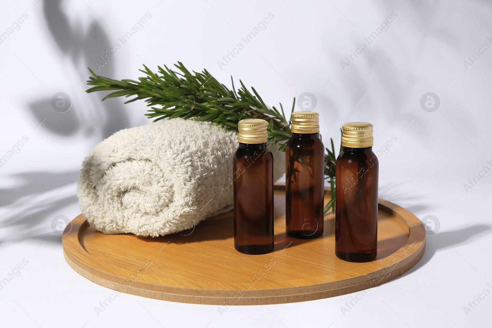 Photo of Bottles of cosmetic products, rolled towel and rosemary on white background