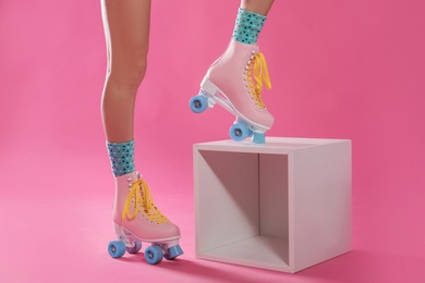 Photo of Young woman with retro roller skates on color background, closeup