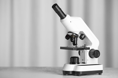 Photo of Modern microscope on table indoors. Space for text