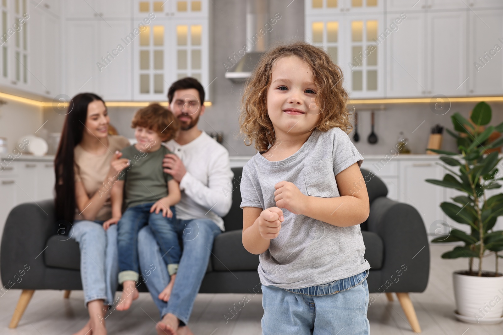 Photo of Happy family having fun at home. Daughter dancing while her relatives resting on sofa, selective focus