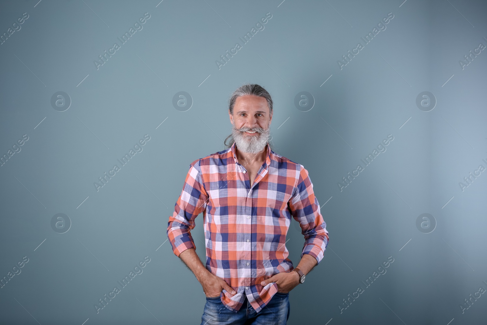 Photo of Handsome bearded mature man on color background