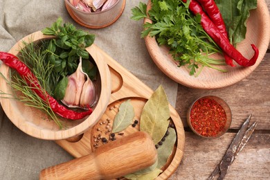 Mortar with pestle and different ingredients on wooden table, flat lay