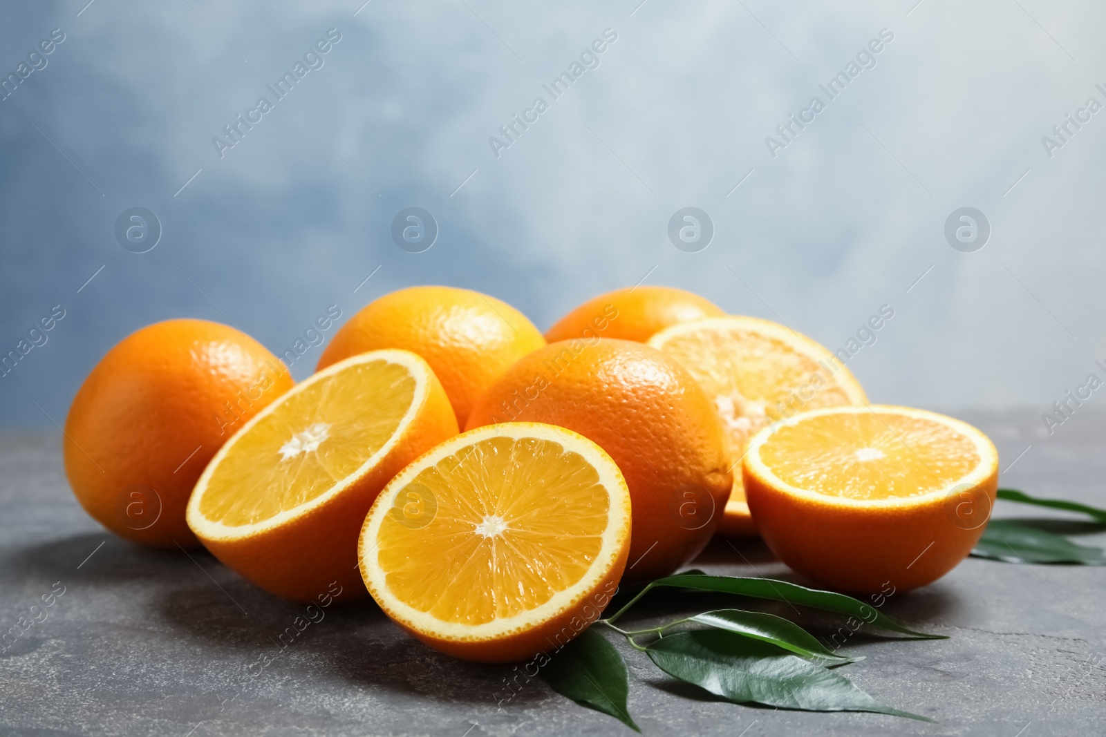 Photo of Fresh oranges with leaves on grey table