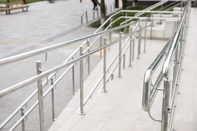 Photo of Tiled ramp with shiny metal railings outdoors